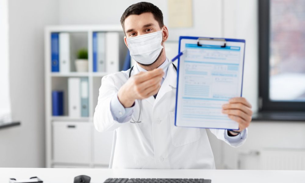 healthcare, medicine and people concept - male doctor with clipboard having video conference at hospital